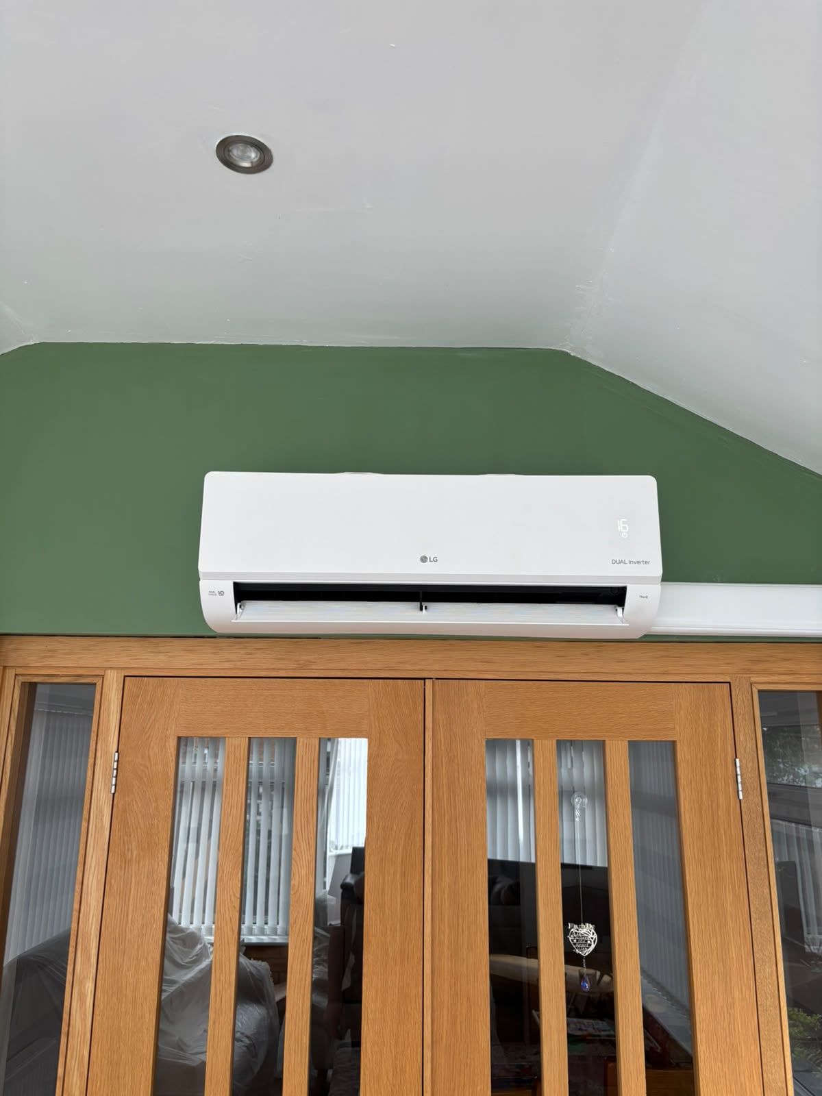 LG DUAL Inverter wall-mounted air conditioning unit installed above oak internal doors
