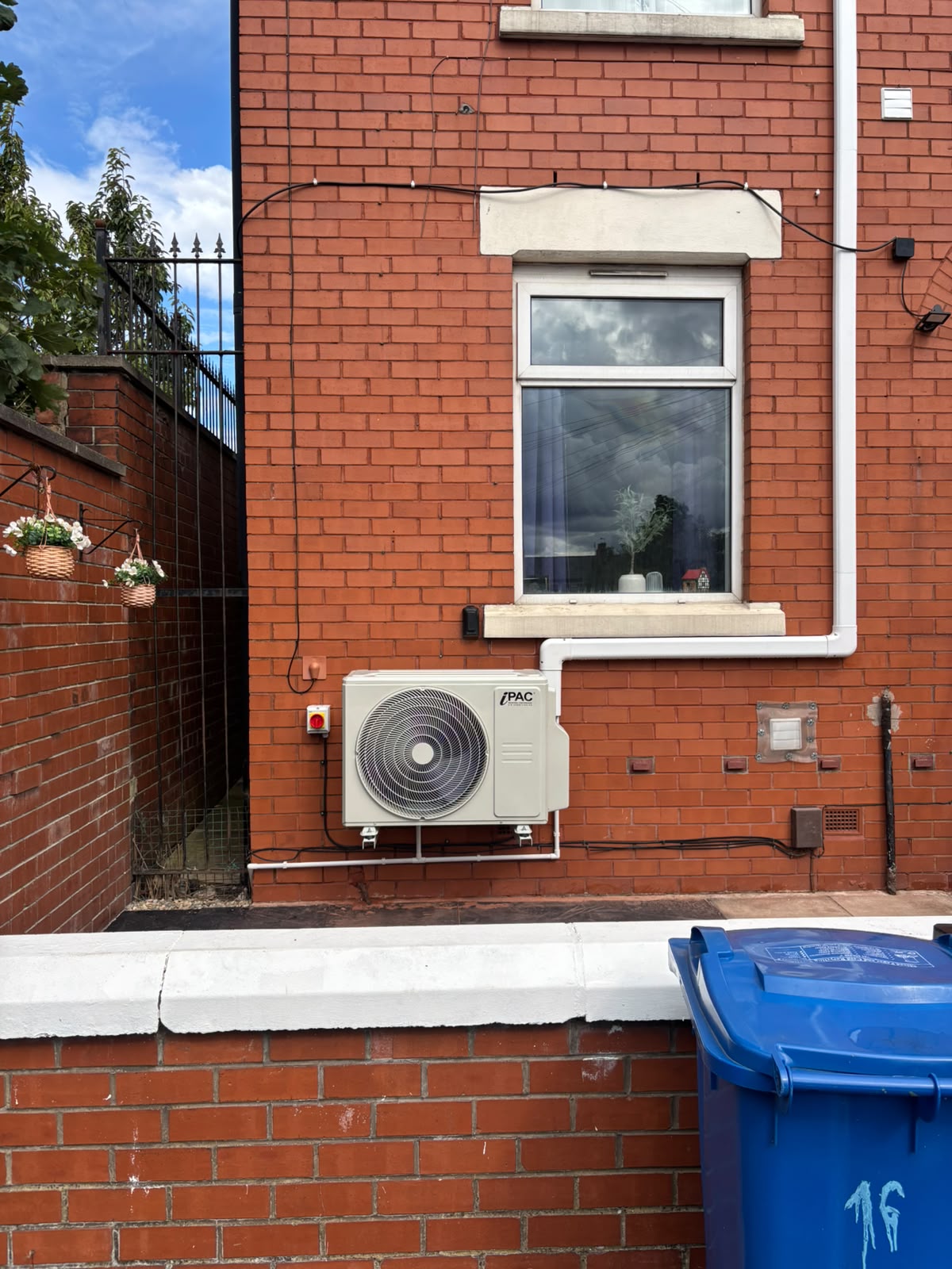 External air conditioning condenser wall-mounted on a red brick house