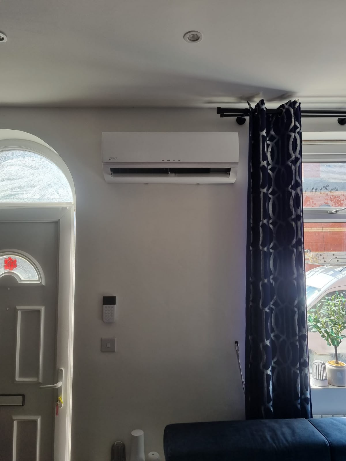 Wall-mounted air conditioning unit installed above a doorway in a home lounge