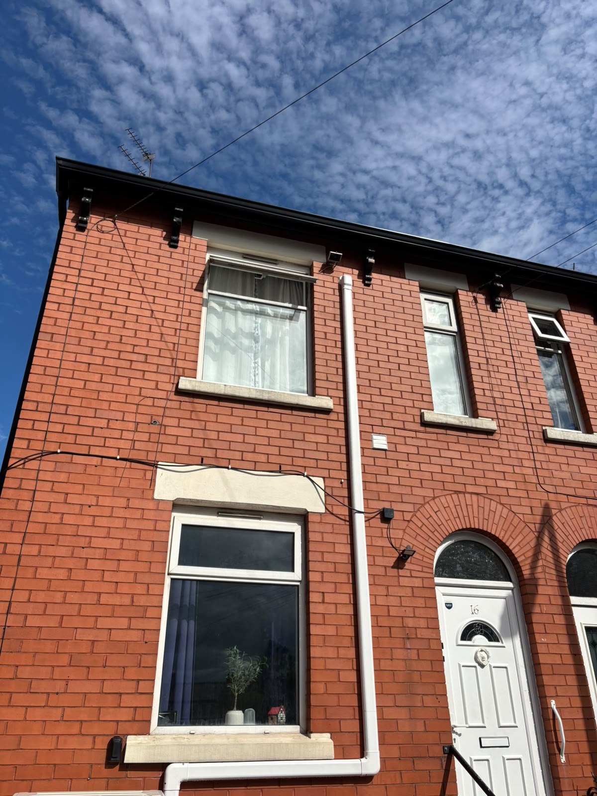 External air conditioning pipework routed up the front of a red brick terraced house